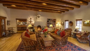 A cozy living room with wooden furniture, a fireplace, and a large rug. - Inn on the Alameda (Santa Fe)