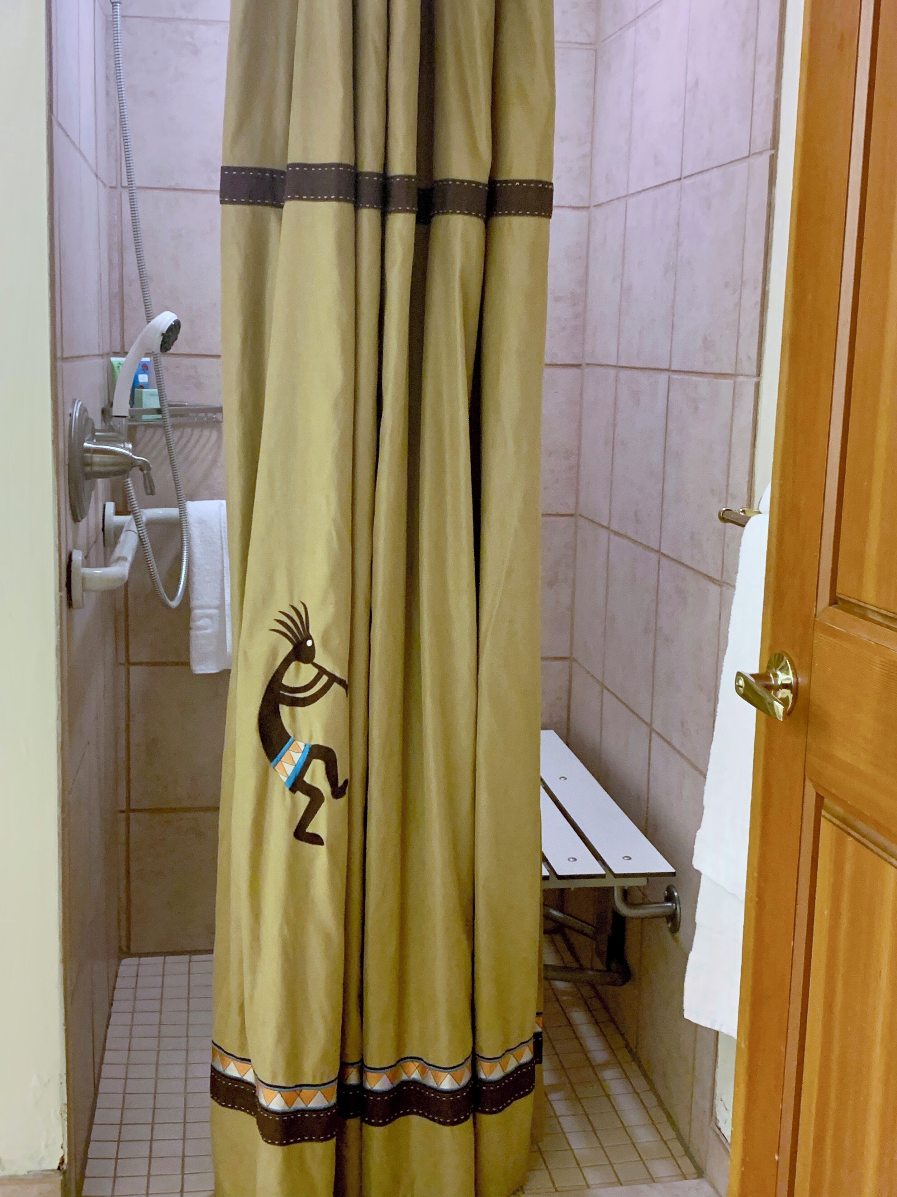 Une salle de bain avec un rideau de douche orné de motifs tribaux, une douchette à main et un porte-serviettes.