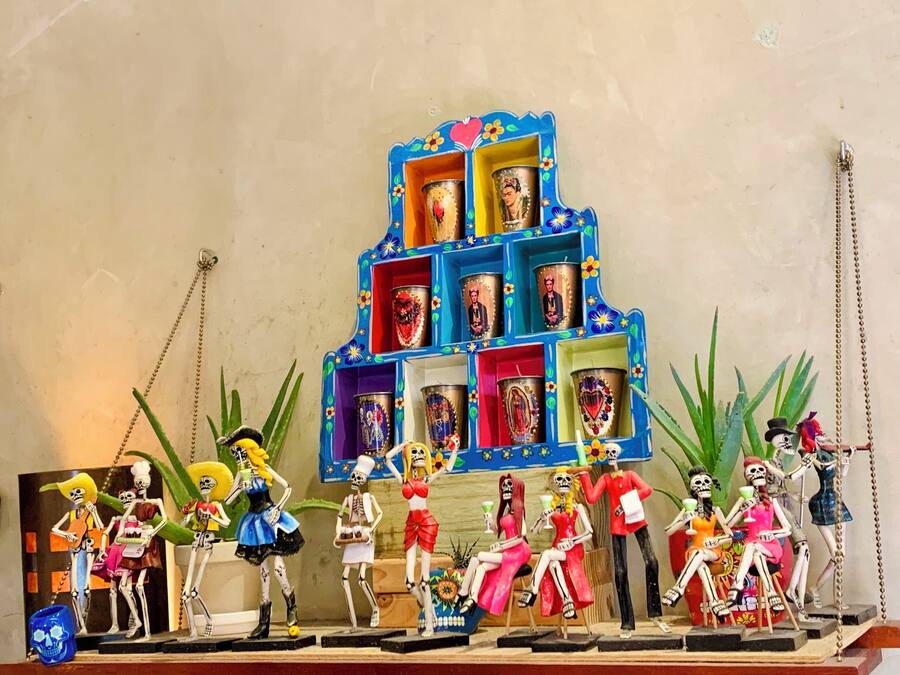 Una exhibición colorida de figuritas de esqueletos y un estante azul con fotografías.