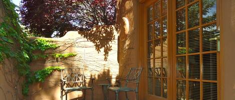 Une terrasse avec un sol en pierre, deux chaises en métal et une petite table.