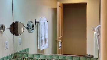 A bathroom with a sink, mirror, towel rack, and a door.