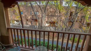 A balcony with a wooden railing, a metal chair, and a small table.