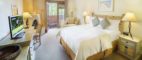 A hotel room with a bed, bedside tables, a desk with a computer, a chair, and a view of the outdoors.