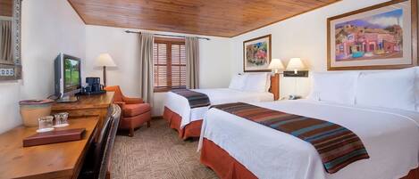 A hotel room with two beds, a desk with a computer, a chair, and a window with curtains.
