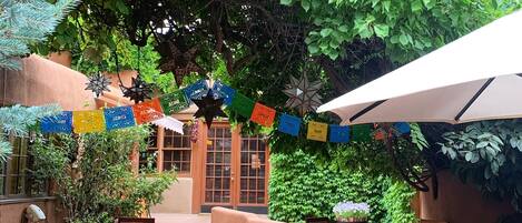 An outdoor patio area with wooden tables and chairs, surrounded by lush greenery and decorative star-shaped ornaments.