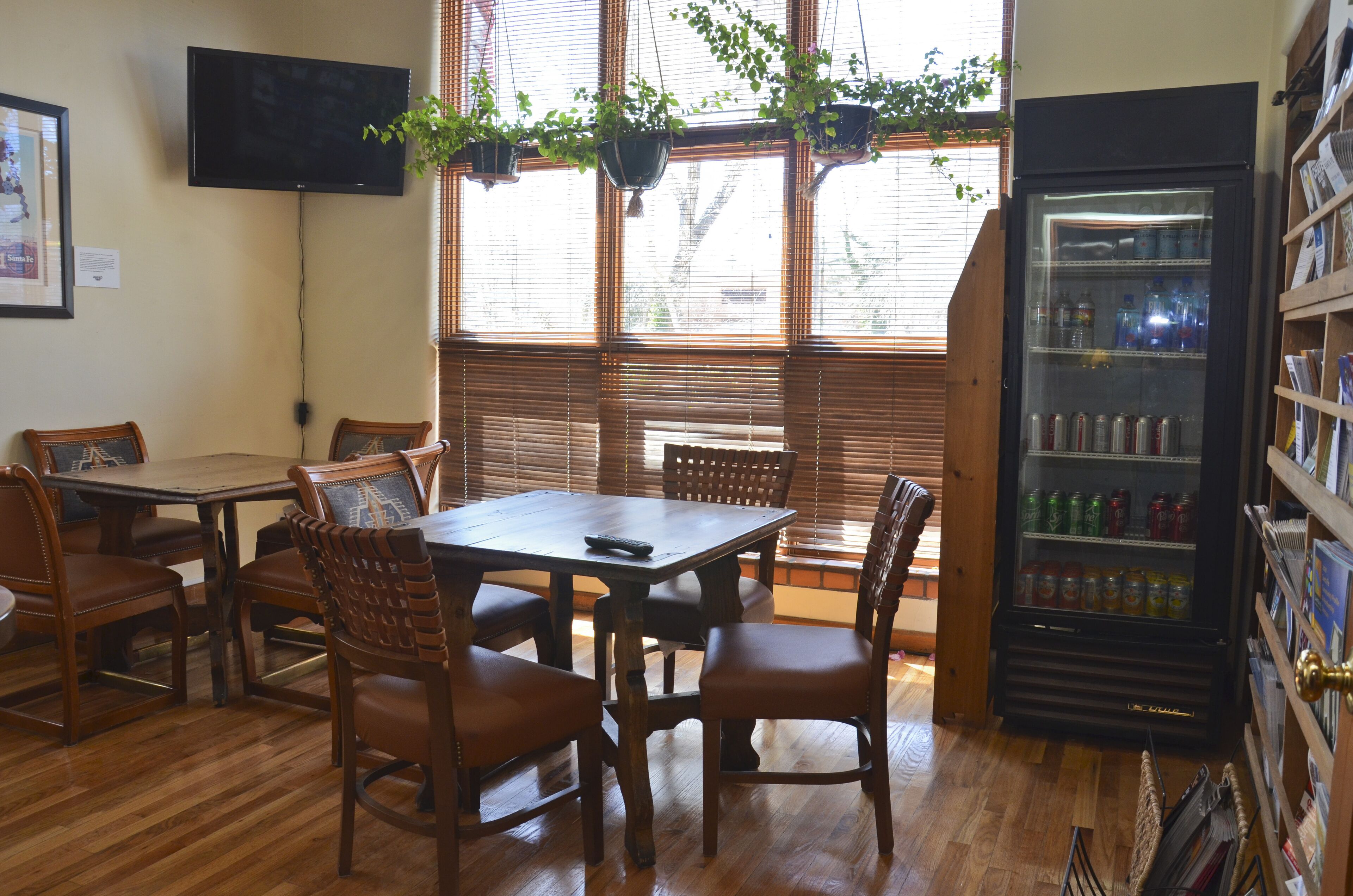 Un interno ristorante con arredi in legno, televisore, piante pensili e un frigorifero per bevande.