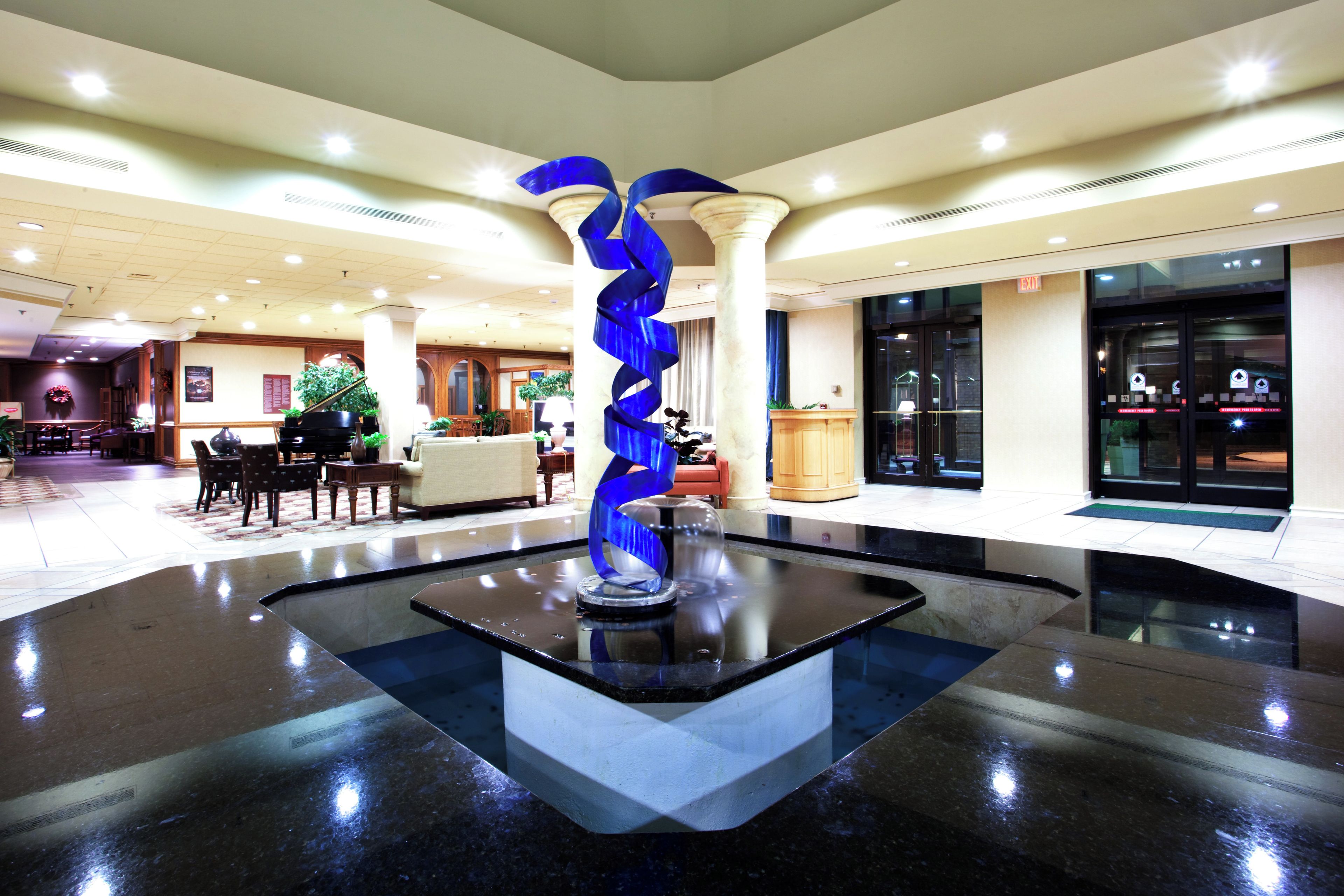 A lobby with a central water feature, seating areas, and a reception desk.