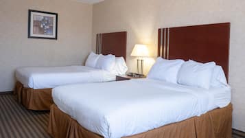 Ein Hotelzimmer mit zwei Betten, jeweils mit weißer Bettwäsche und braunen Betttüchern. An der Wand hängt ein gerahmtes Bild und auf dem Nachttisch steht eine Lampe.