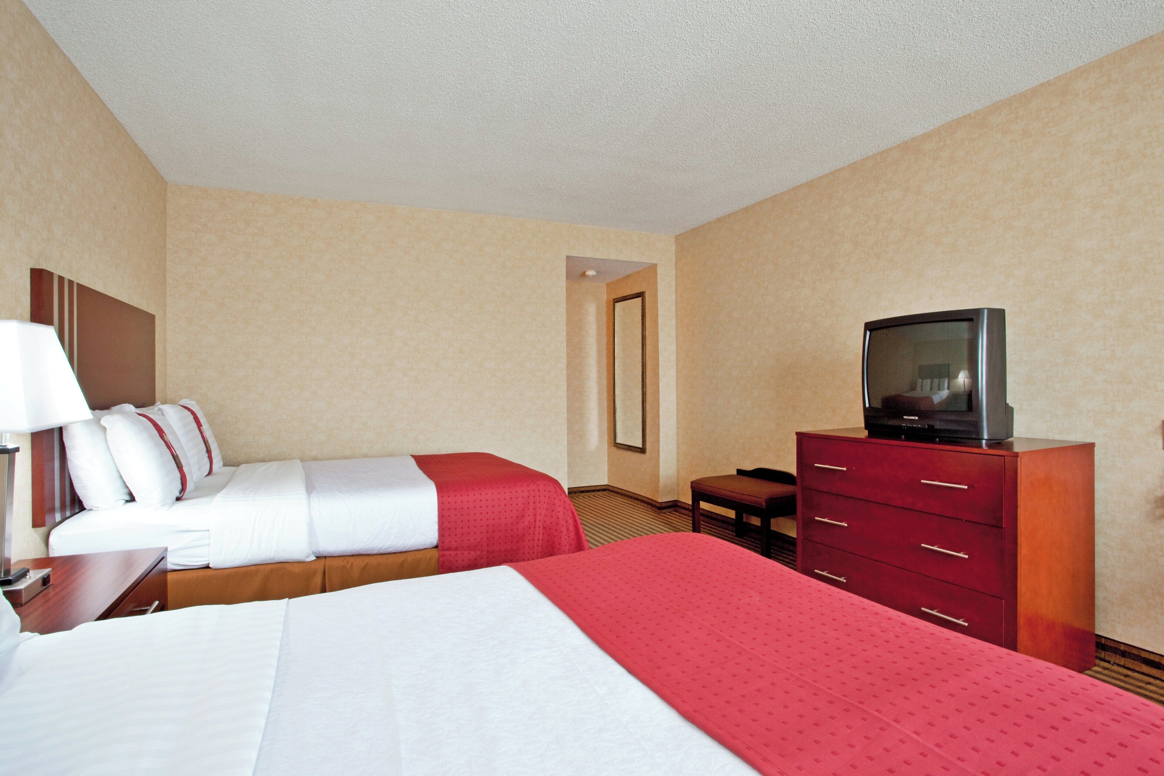 Una habitación de hotel con dos camas, televisión, escritorio y cómoda.