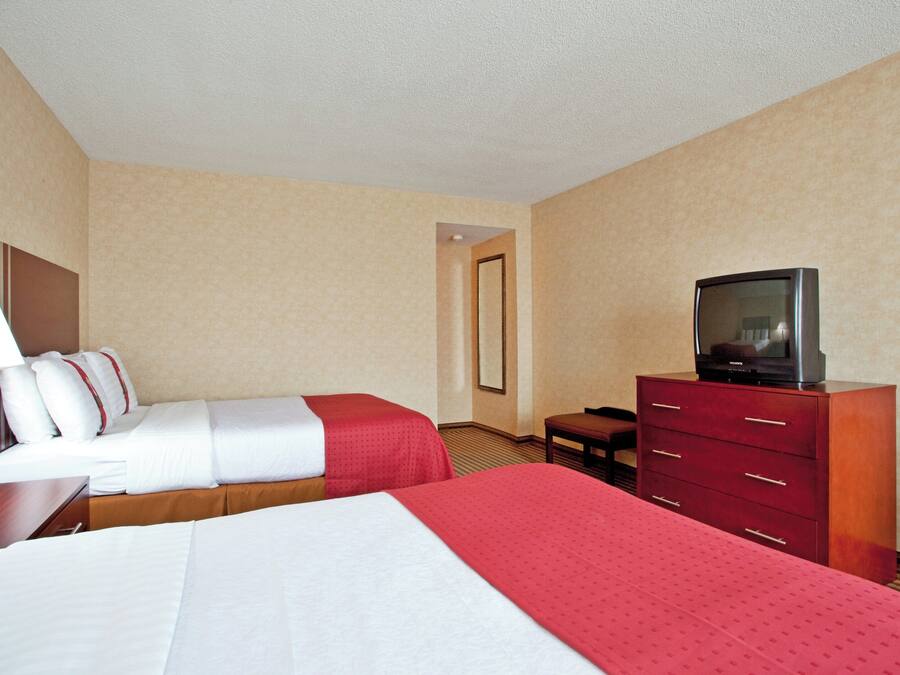 Una habitación de hotel con dos camas, televisión, escritorio y cómoda.