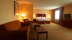 A hotel room with a bed, a sofa, a desk, a TV, and two lamps. - Lynchburg Grand Essential (Lynchburg)