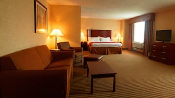 Una habitación de hotel con cama, sofá, escritorio, televisión y dos lámparas.