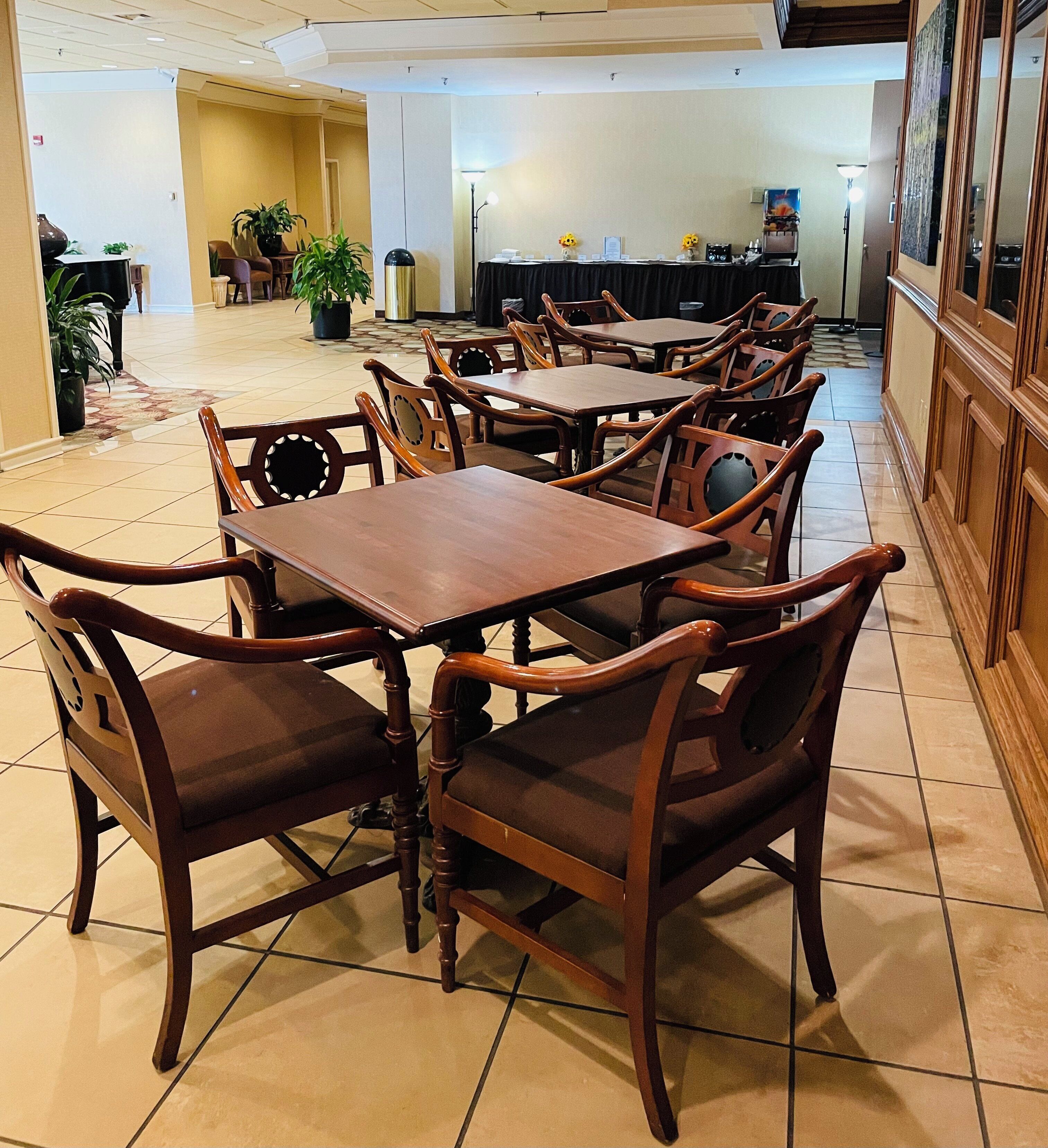 Comedor con mesas y sillas de madera, una planta en maceta y un mostrador con caja registradora.