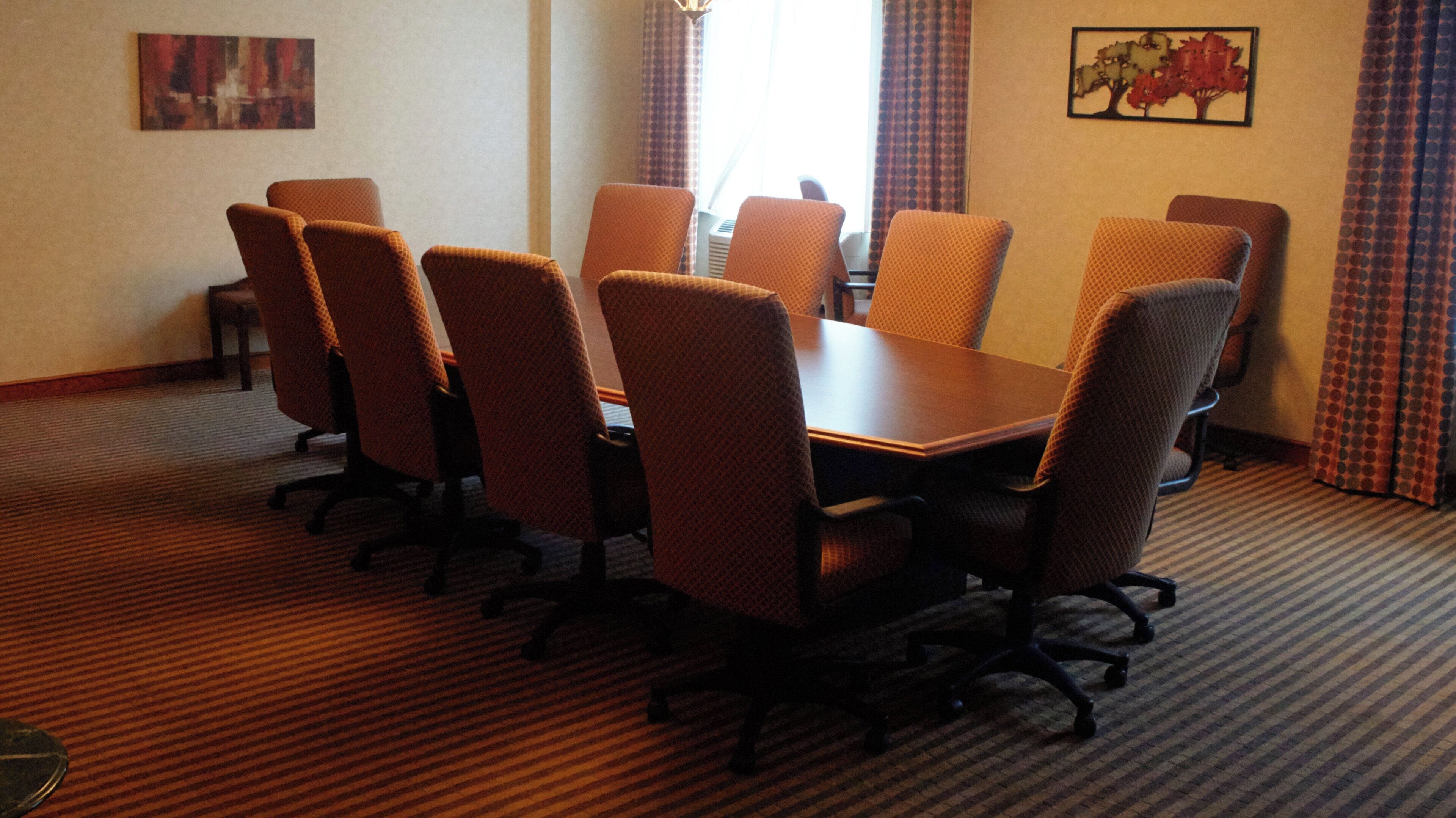 A conference room with a rectangular table surrounded by eight chairs.