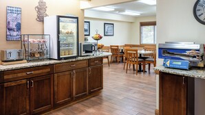 Un espace cuisine équipé d’un réfrigérateur, d’un four à micro-ondes, d’un grille-pain et d’une machine à crêpes en libre-service.