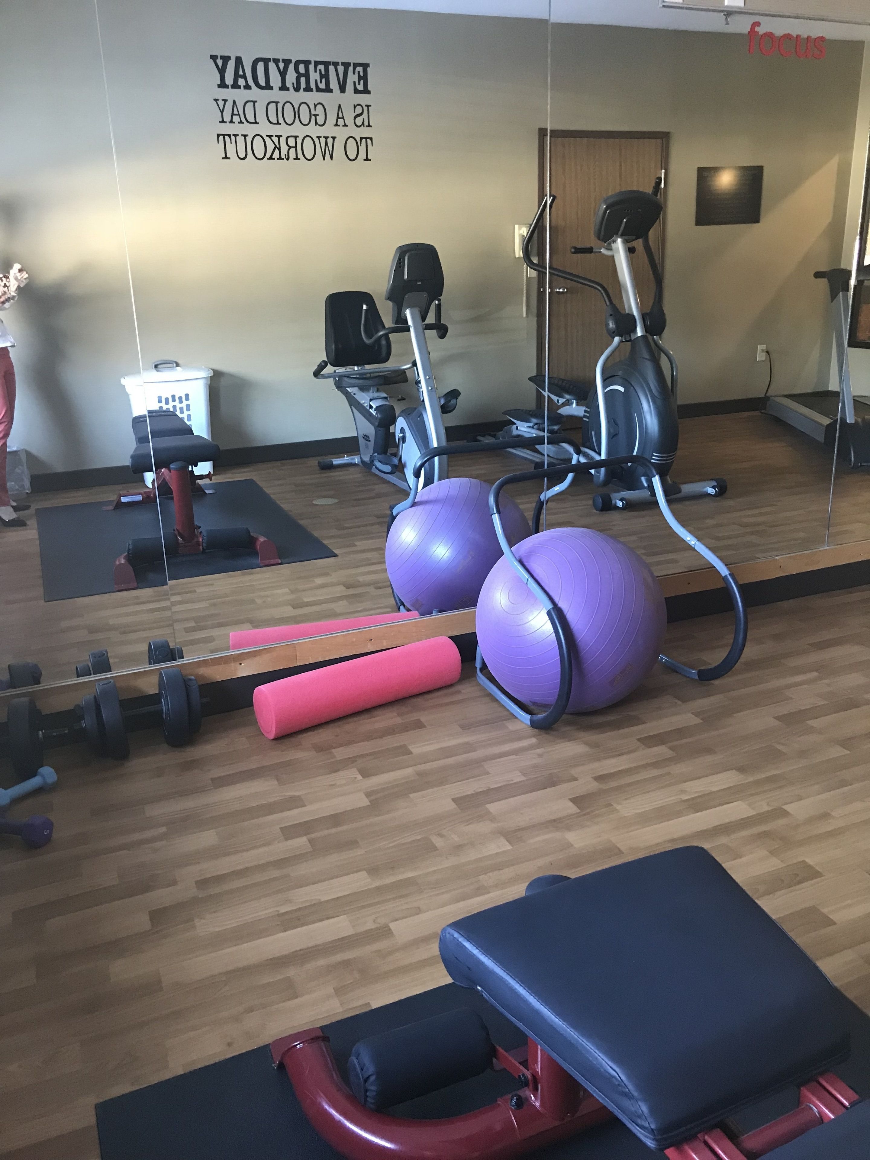 Une salle de sport équipée de matériel d’exercice, d’un miroir et de citations motivantes affichées sur les murs.