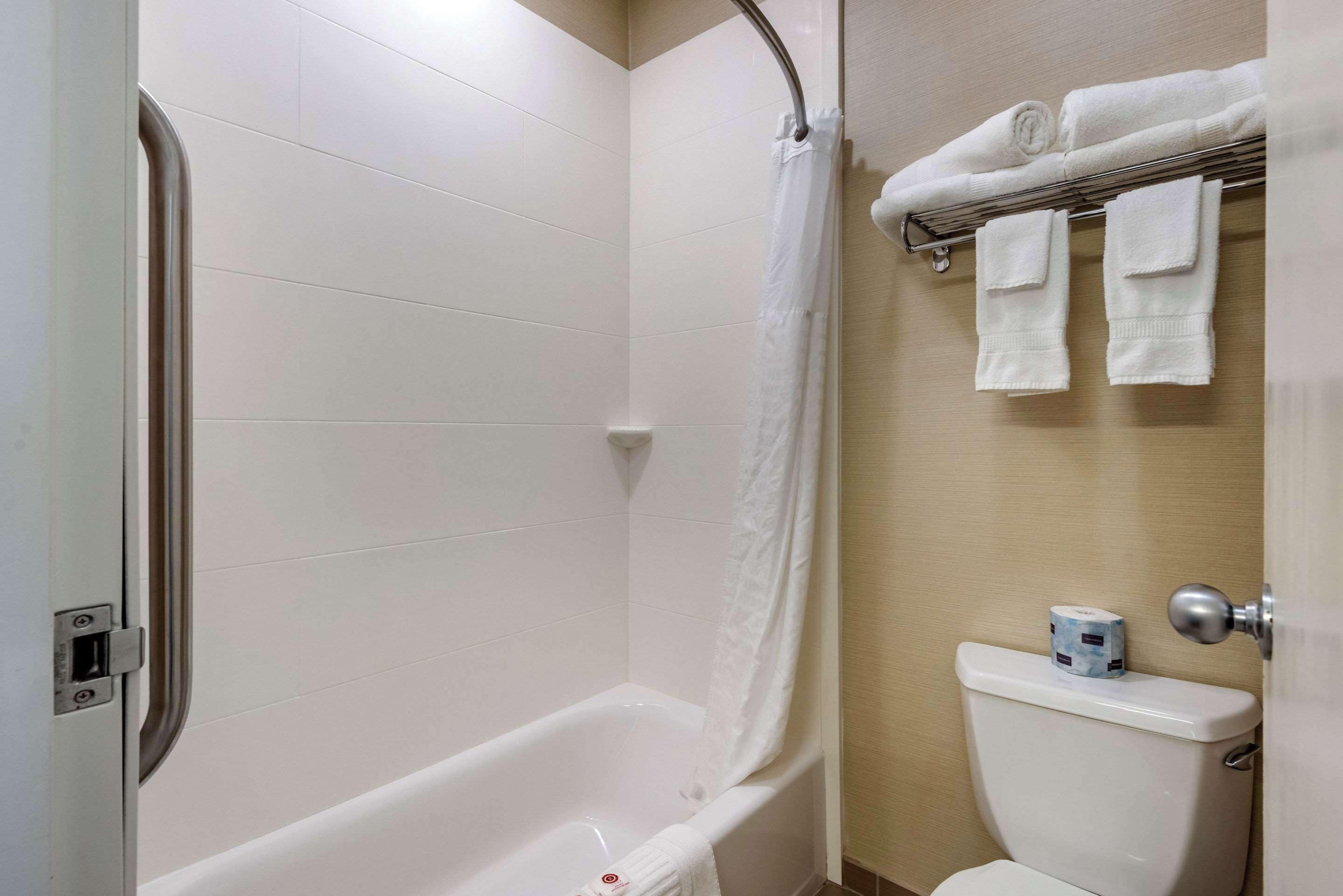 A bathroom with a bathtub, a toilet, and a towel rack with towels.