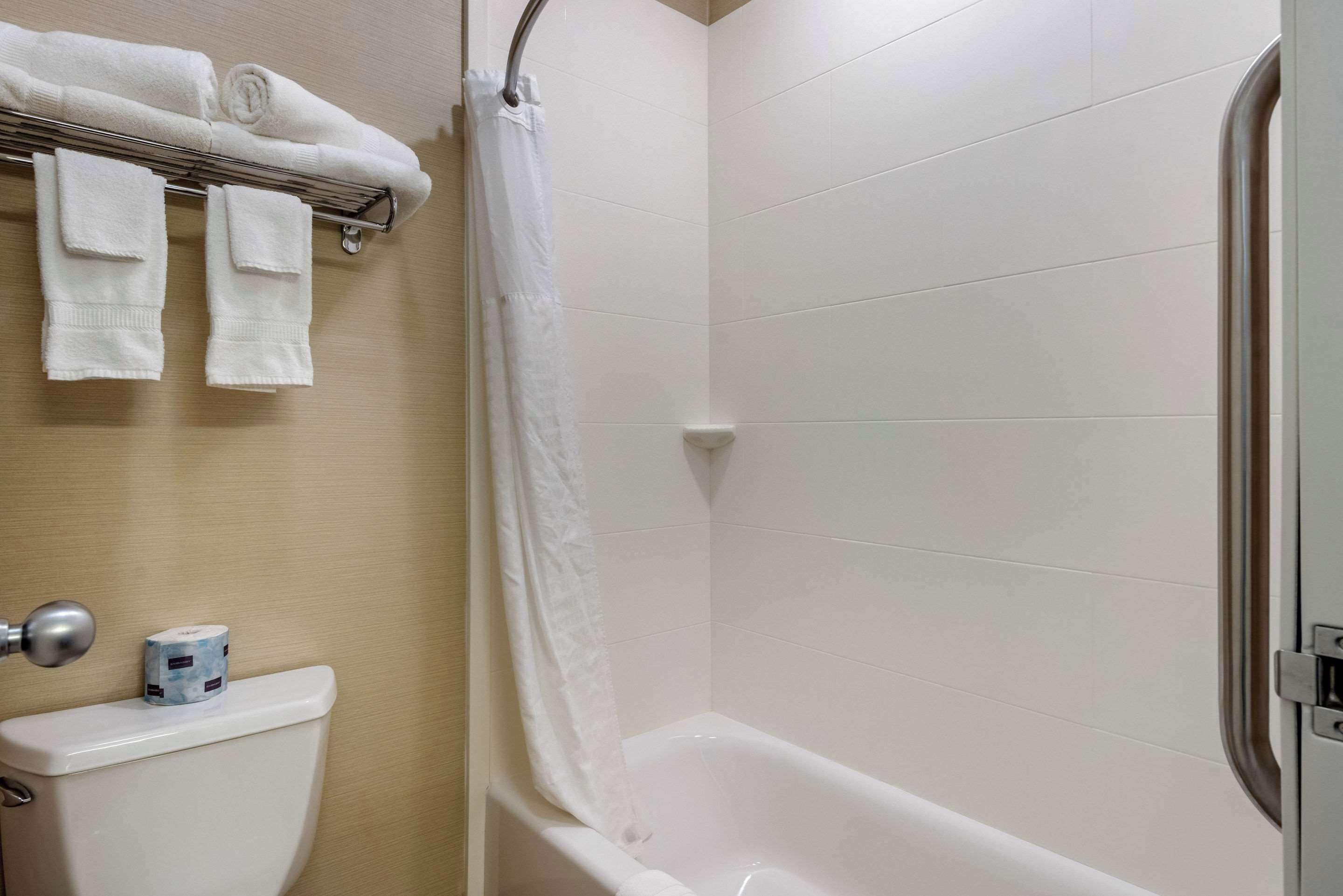 Een badkamer met een toilet, een bad en een handdoekrek met handdoeken.