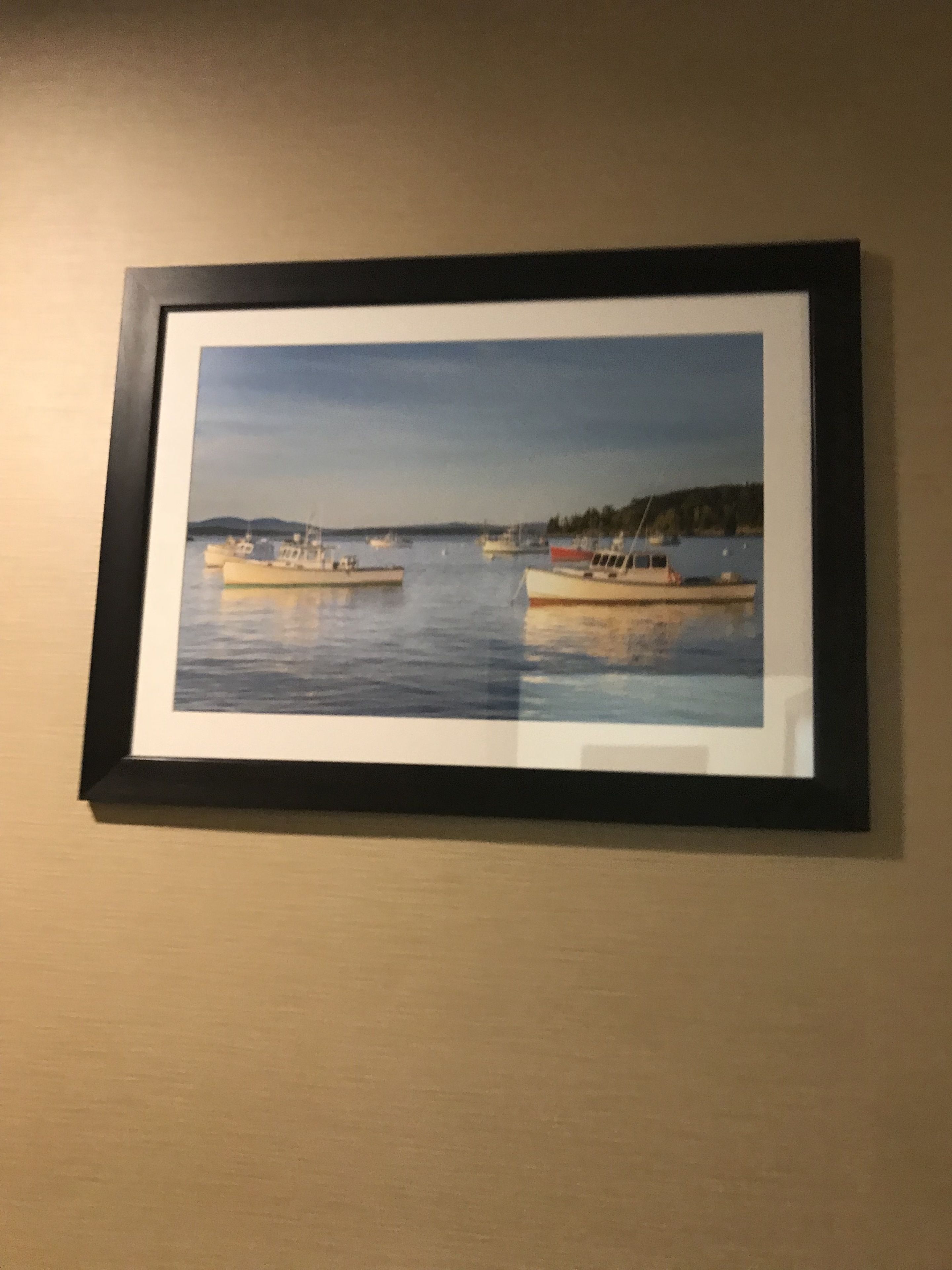 A framed picture of a harbor scene with boats on the water.