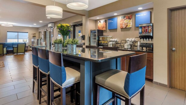 Una cocina moderna con una isla central, taburetes de bar, una zona para café y un refrigerador.
