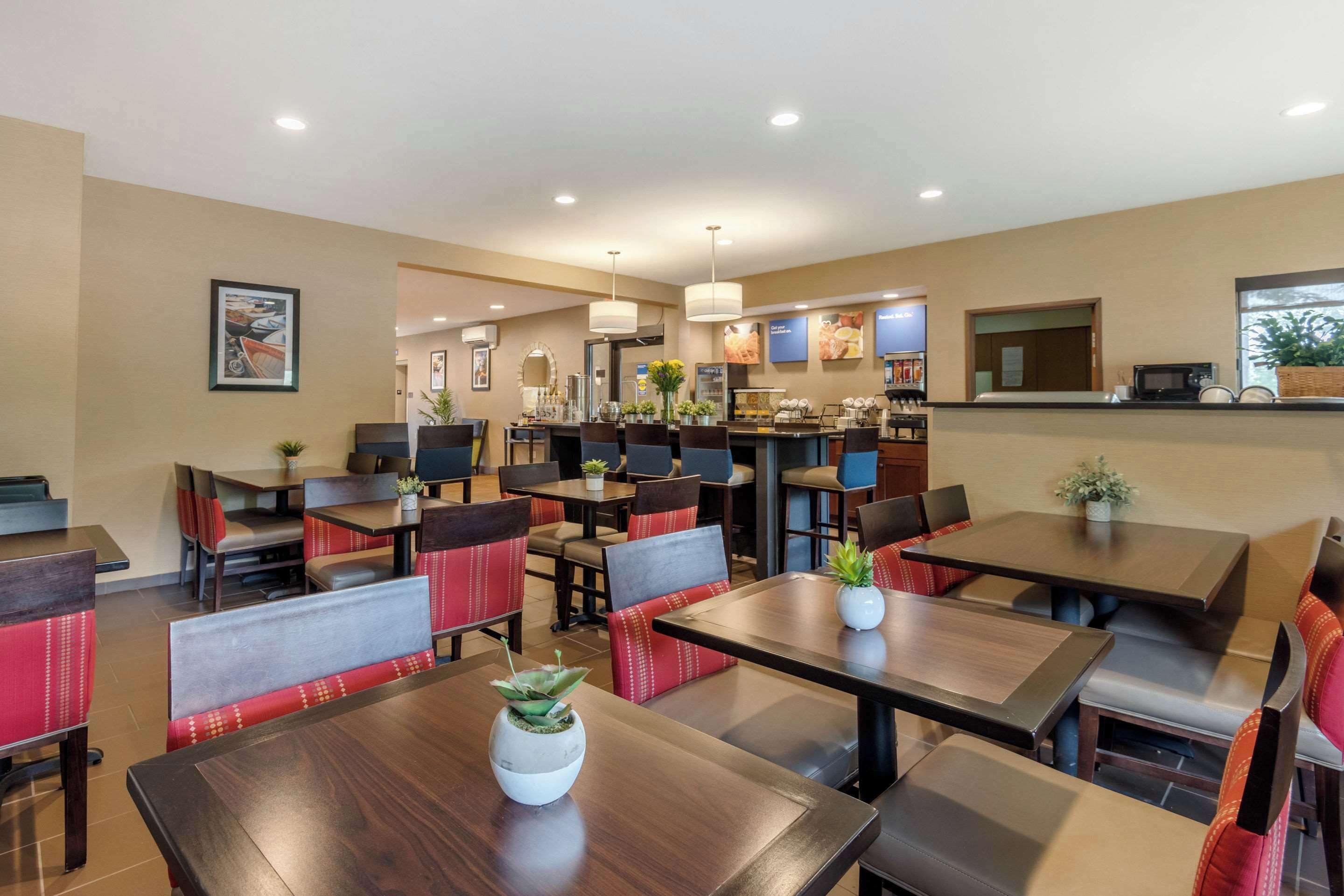 A restaurant with booths and tables, some with plants. There are ceiling lights and a counter with a menu.