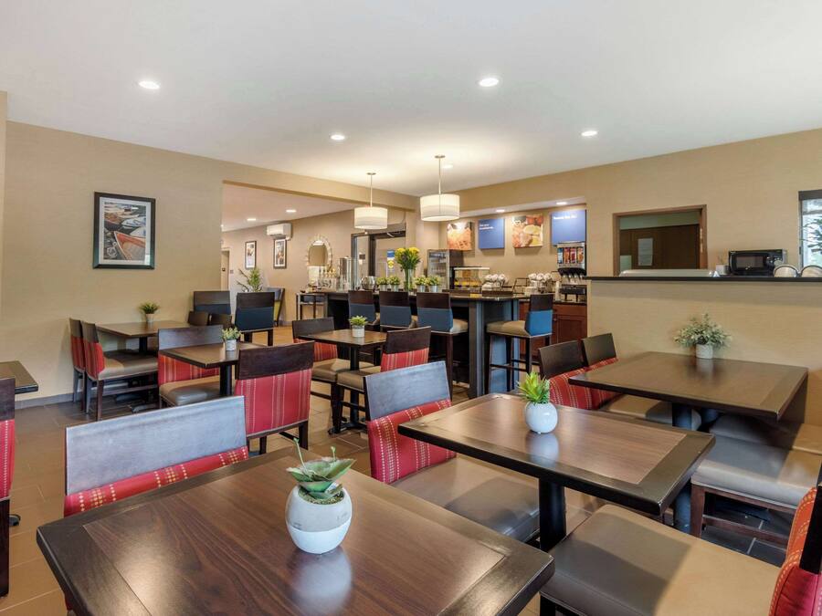 A restaurant with booths and tables, some with plants. There are ceiling lights and a counter with a menu.
