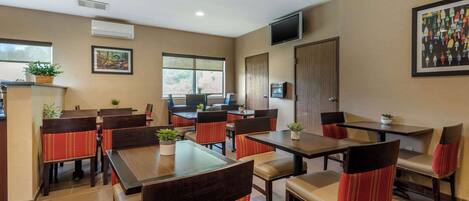 A restaurant with booths and tables, air conditioning, a television, and a window with a view.