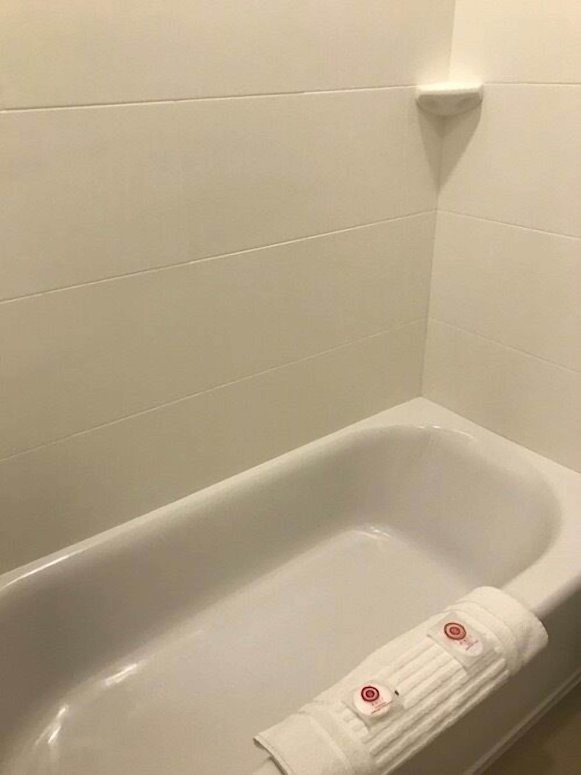 A white bathtub with a towel folded at the bottom.