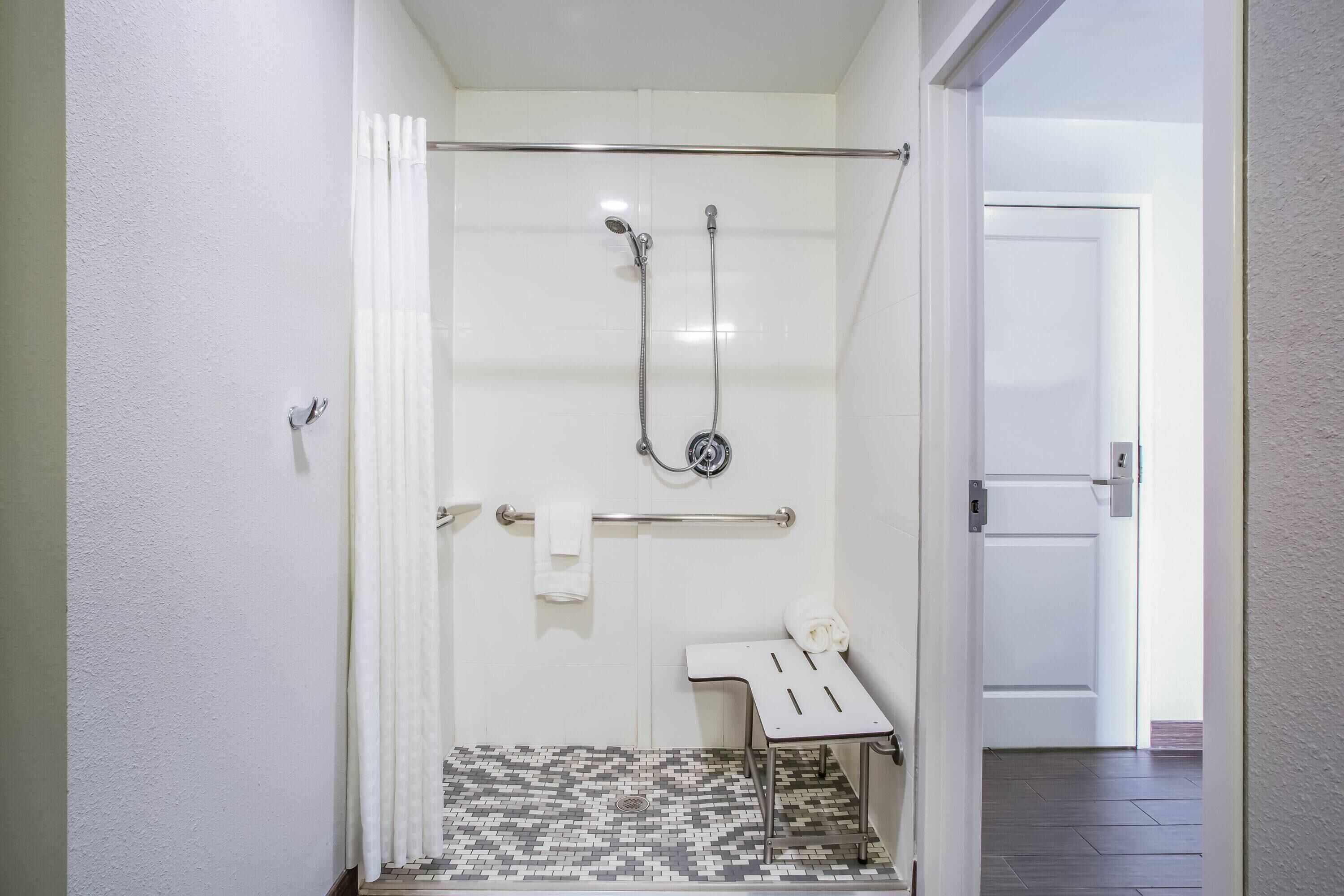 A bathroom with a shower, a towel rack, and a small table.