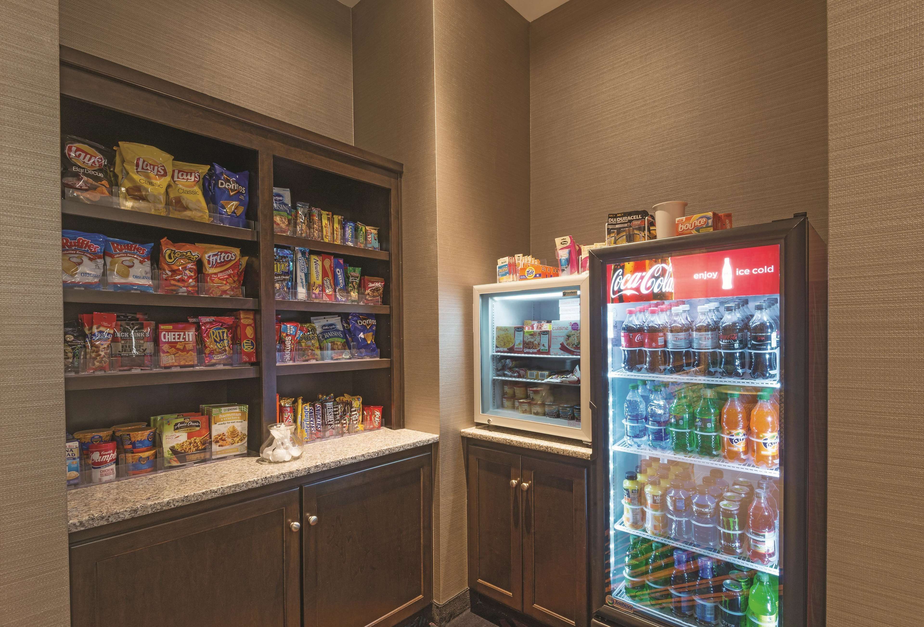 A snack and beverage vending area with various snack options and a Coca-Cola refrigerator.