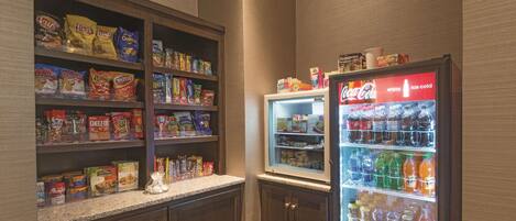 A snack and beverage vending area with various snack options and a Coca-Cola refrigerator.