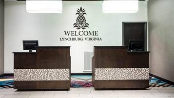 A reception area with two wooden reception desks, a welcome sign, and a patterned carpet.