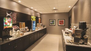 Un área de cocina moderna con cafetera, dispensador de jugo y máquina para hacer gofres.