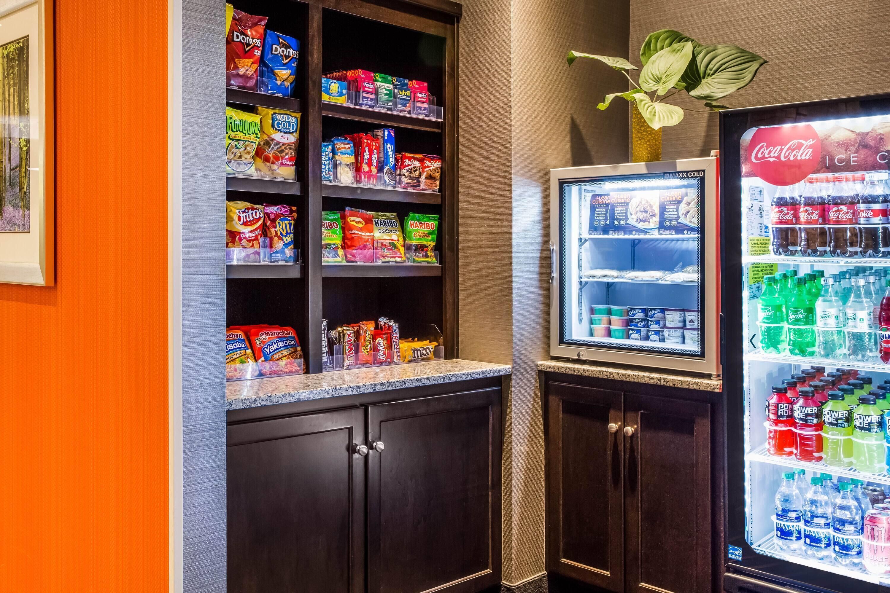 Ein Getränkeautomat mit Snacks und Erfrischungen, ein Kühlschrank mit Getränken und ein Blumentopf.