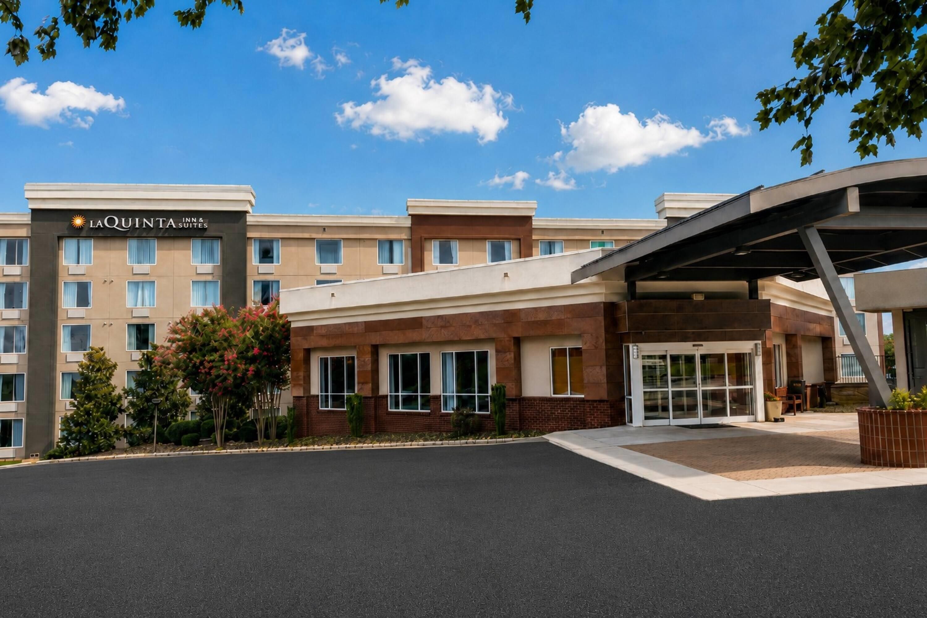 A hotel with a modern entrance, a covered waiting area, and a clear sky.