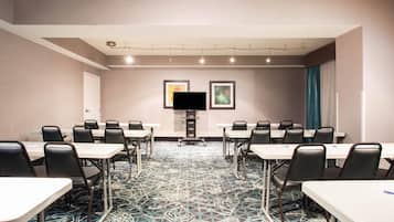 A conference room with tables and chairs, a flat-screen TV, and framed artwork on the wall.