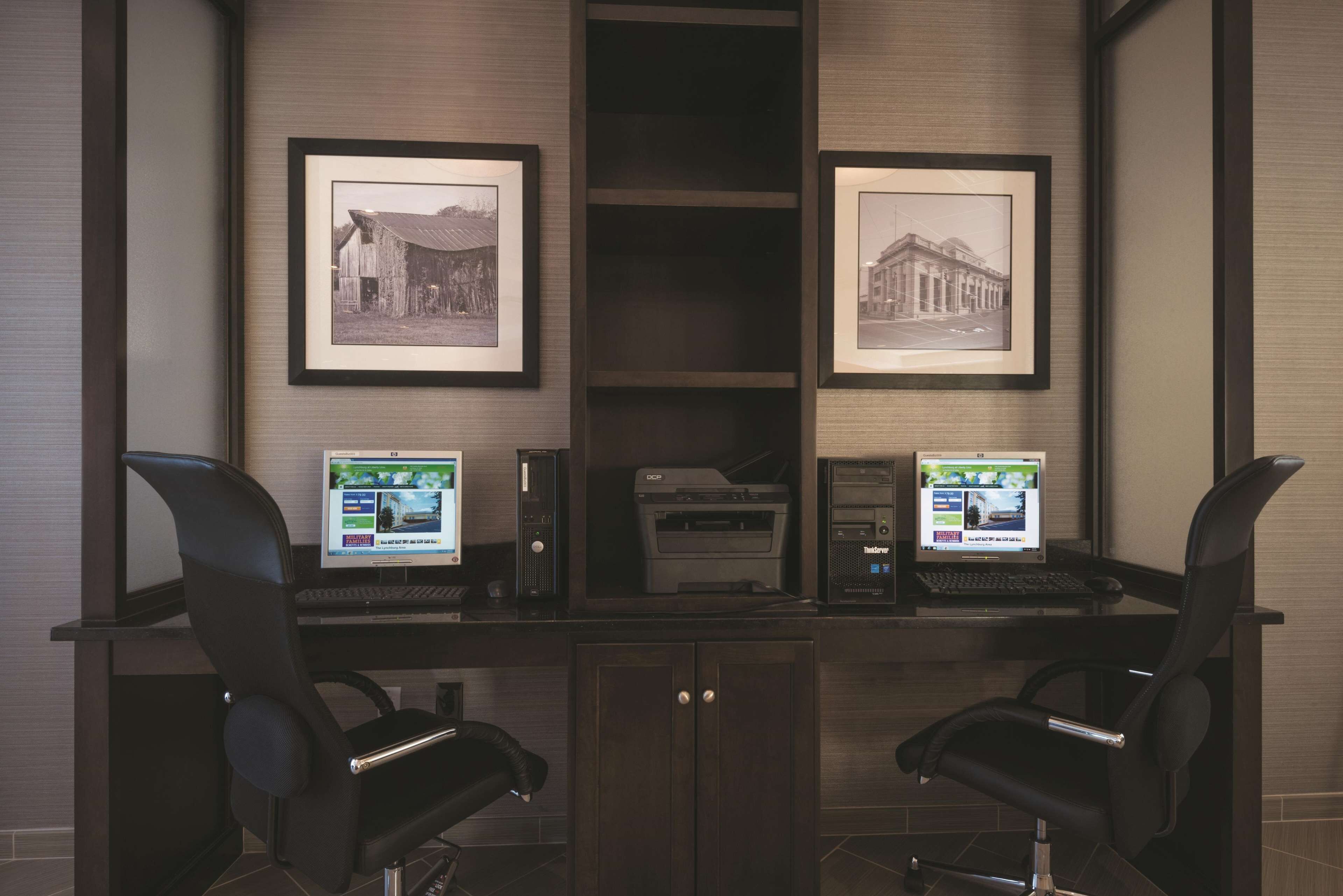 A conference room with two desks, each with a laptop and a framed picture on the wall.