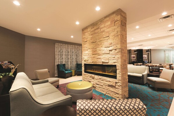 A modern living room with a stone accent wall, a fireplace, and contemporary furniture. - La Quinta Inn & Suites by Wyndham Lynchburg at Liberty Univ. (Lynchburg)
