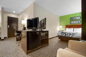 Une chambre d’hôtel équipée d’un lit, d’un bureau avec une télévision, d’une chaise et d’un four à micro-ondes.