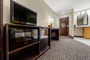 A hotel room with a flat-screen TV, a minibar, a lamp, and a mirror. - Sleep Inn & Suites Omaha Airport (Omaha)