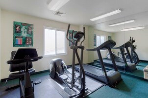 Un gimnasio con cintas de correr, una bicicleta estática y una máquina de remo.