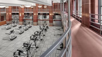 Et rummeligt fitnessrum med flere løbebånd, motionscykler og styrkemaskiner stillet op i rækker.