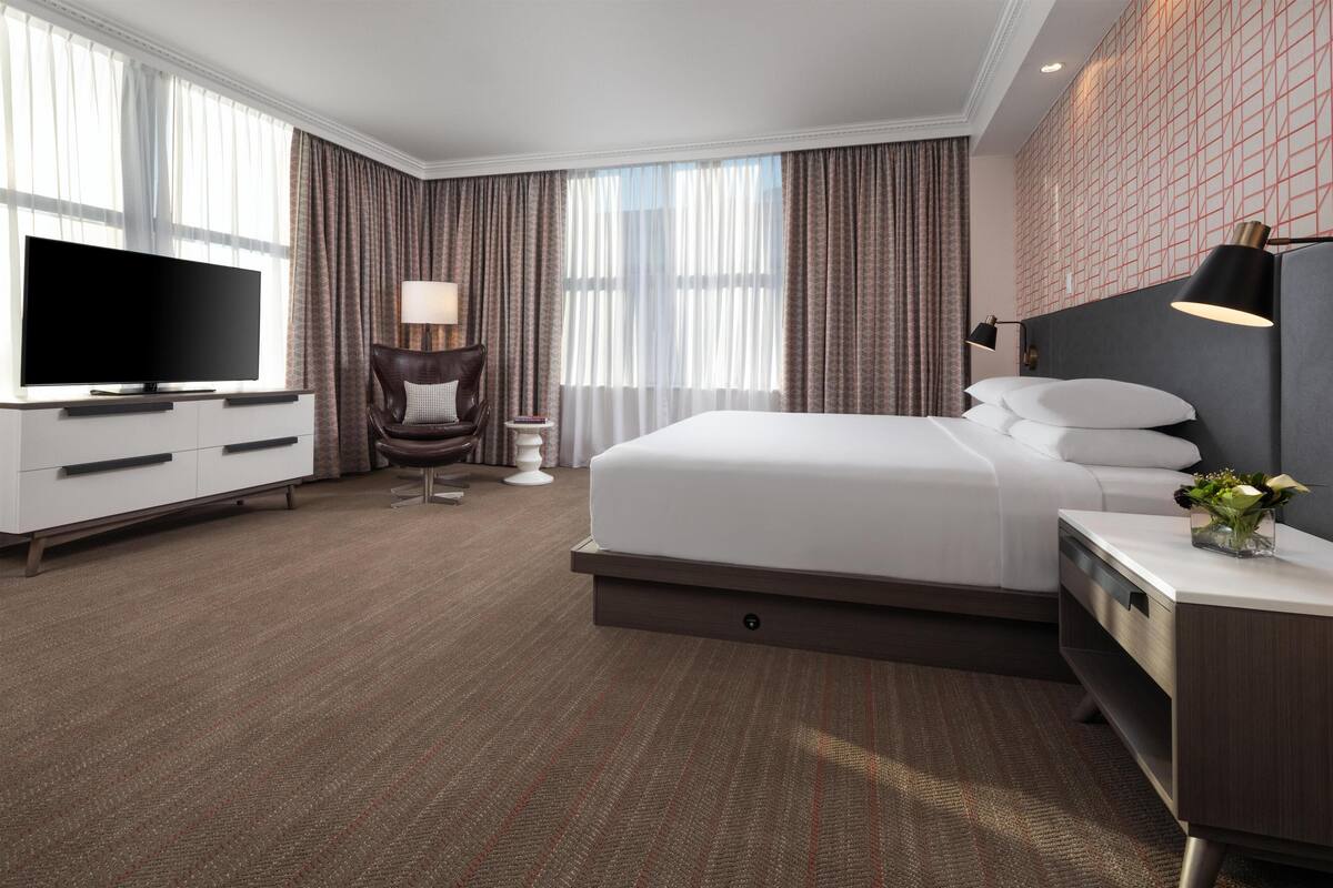 Une chambre d’hôtel moderne équipée d’un grand lit, d’une télévision, d’un bureau et d’une chaise.
