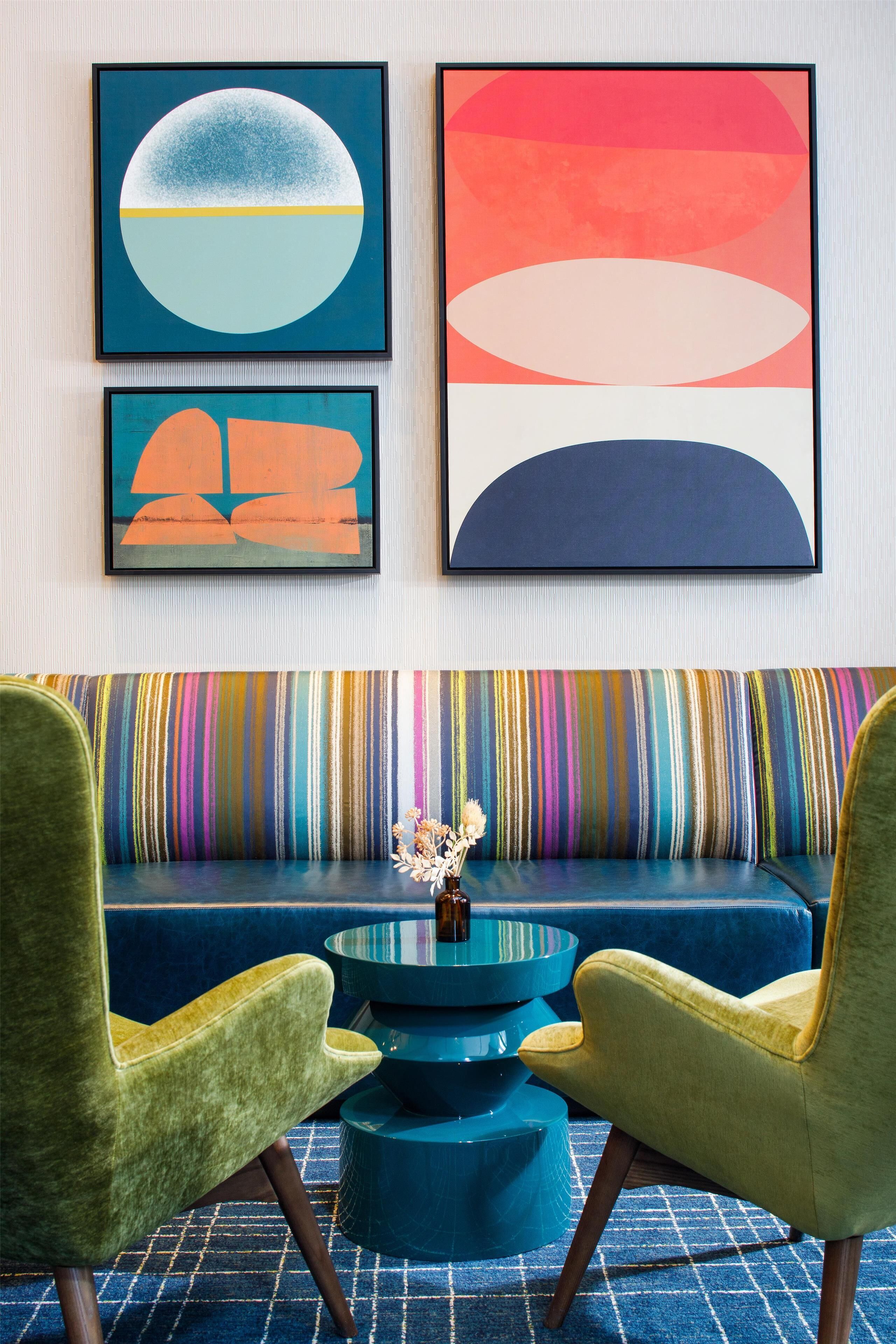 Une pièce comprenant un canapé, deux fauteuils et trois œuvres d’art encadrées accrochées au mur.