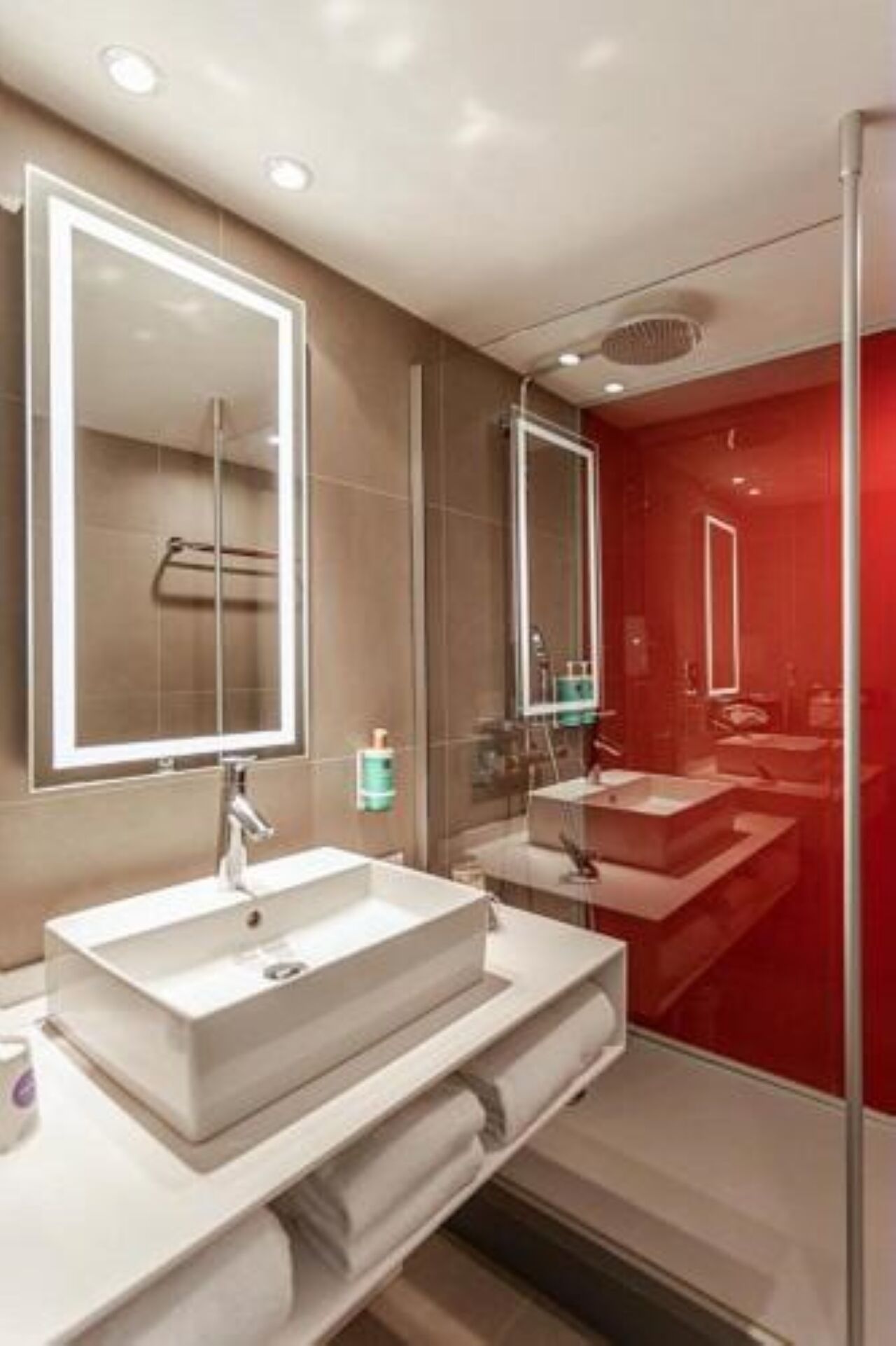 A modern bathroom with a large mirror, two sinks, and a glass shower enclosure.