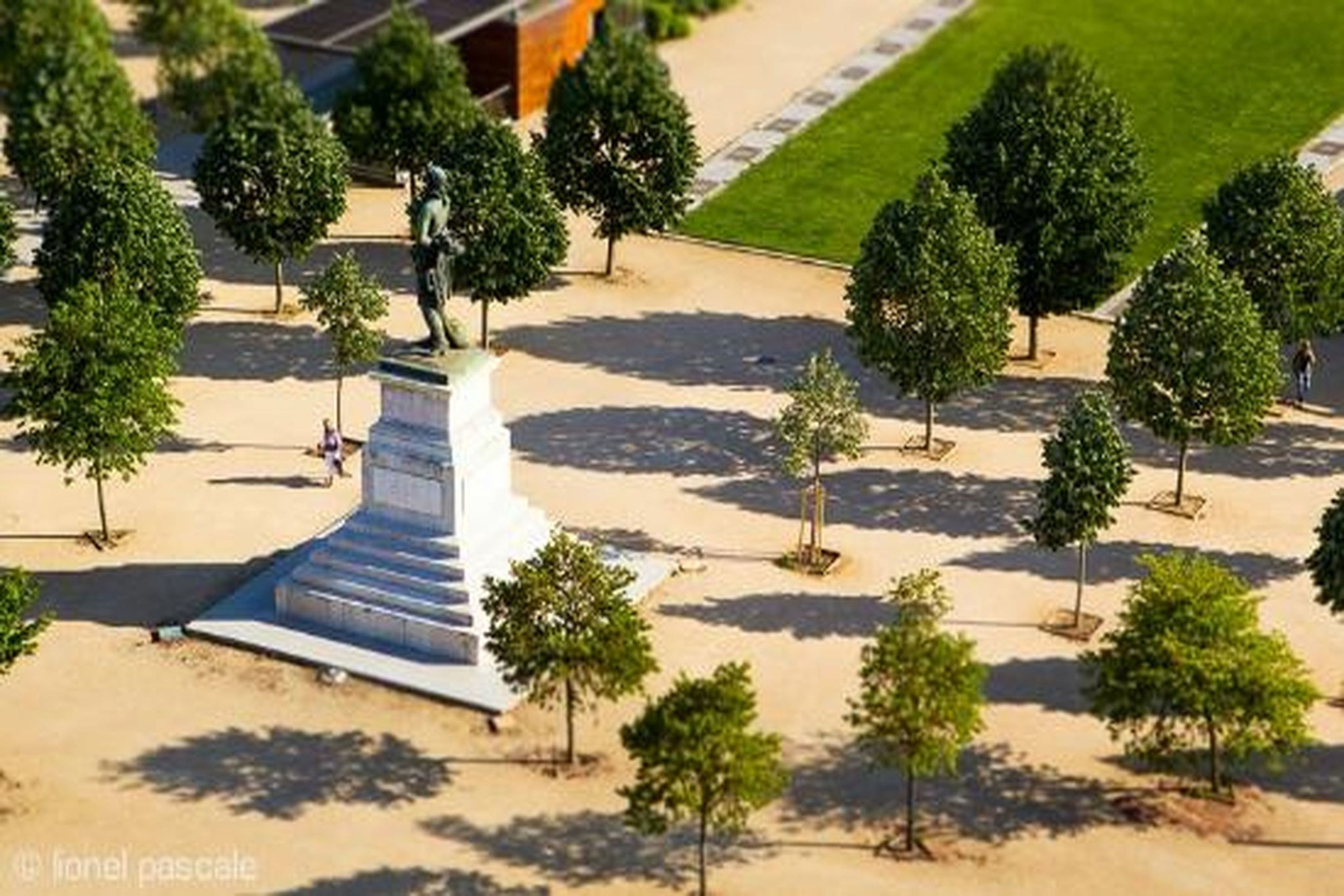 A statue on a pedestal surrounded by trees in a landscaped area.