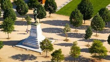 A statue on a pedestal surrounded by trees in a landscaped area.