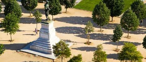 A statue on a pedestal surrounded by trees in a landscaped area.
