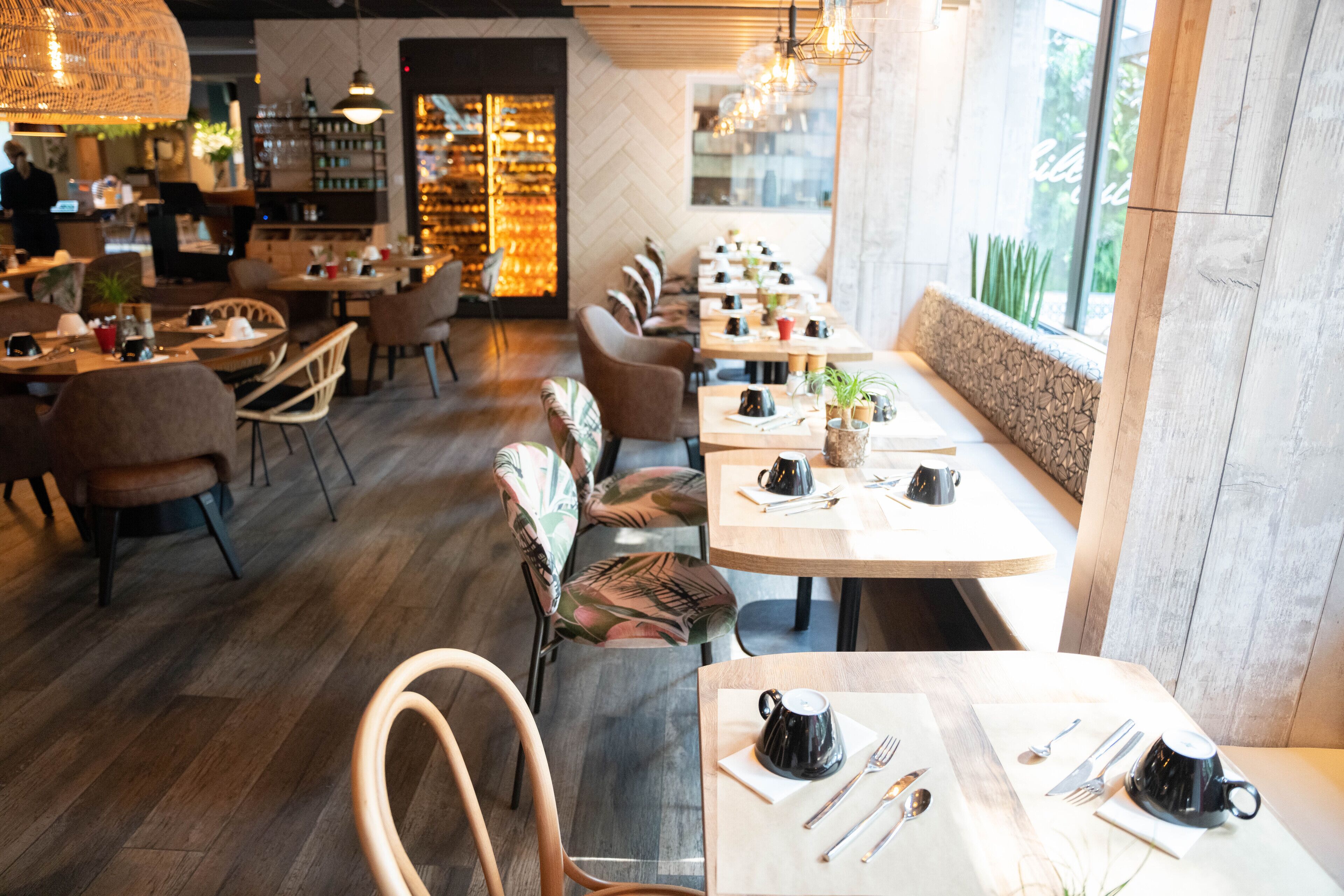 A modern restaurant with wooden flooring, comfortable seating, and a long counter.