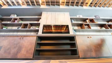 A modern interior with a built-in fireplace, wooden shelves, and a herringbone-patterned floor.